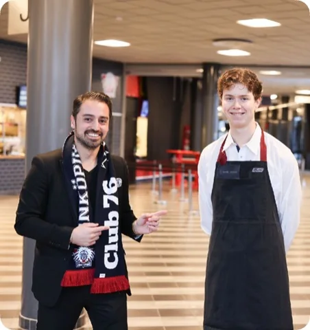 Two people in an arena setting, one wearing an apron.