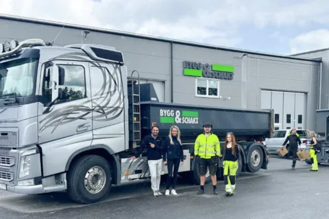 A group of people in front of a truck outside an industrial building.
