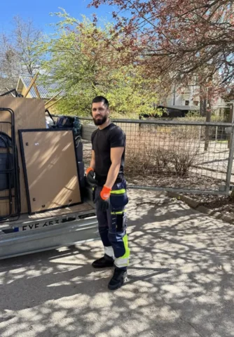 A person in workwear and gloves beside a loaded trailer.